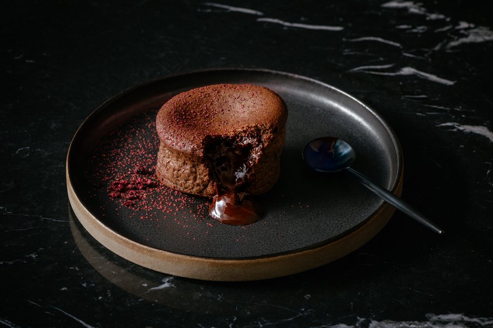 A chocolate fondant cake with melted chocolate center on a plate.